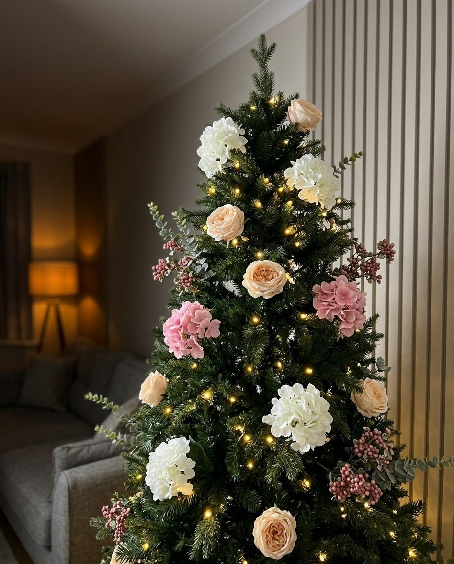 Close-up of The Winter Bloom Flower Christmas Tree lit at night, with artificial roses, white and pink hydrangeas and berry sprays