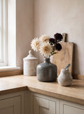 The Kitchen Corner — grey Chive vase with cream and chocolate blooms, white cannister and stone pear on an oak worktop