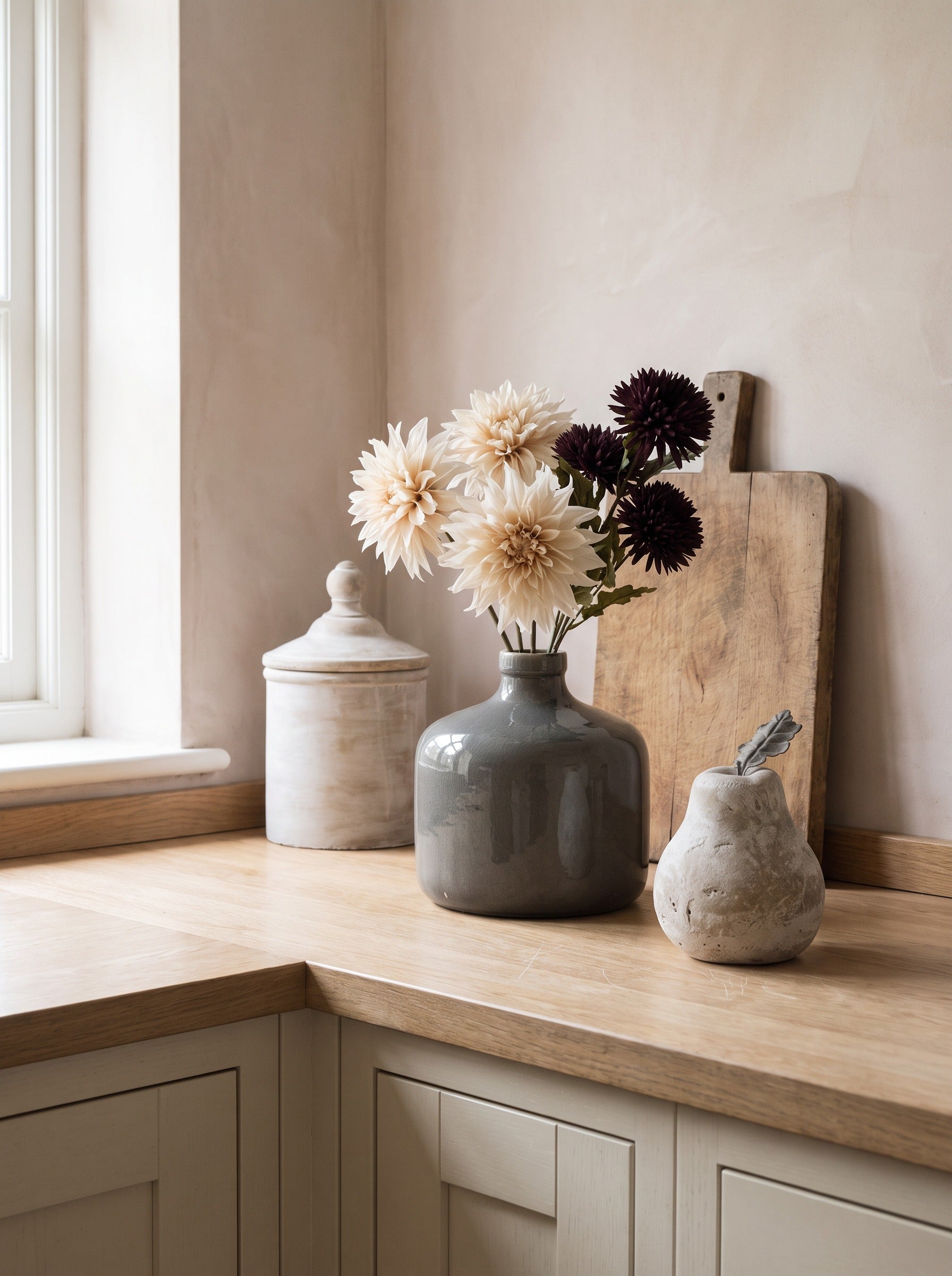 The Kitchen Corner — grey Chive vase with cream and chocolate blooms, white cannister and stone pear on an oak worktop