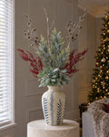 The Blue Flora Snowy Woodland Arrangement: artificial snowy woodland branches, frosted pine, red berry sprays and lambs ear in the Classic Blue Flora Juniper Vase, on a stone plinth in a Christmas living room