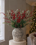 The Christmas Hearth Berry & Pine Arrangement: artificial red berries, frosted cypress fir with pinecones, eucalyptus and gold pine sprays in the Aged Stone Ceramic Vase, on a stone plinth in a Christmas living room