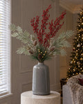 The Garda Frosted Berry Arrangement: artificial red berry sprays, silver wattle, frosted cypress and a gold pine spray in the grey glazed Garda Liv Vase, on a stone plinth in a Christmas living room