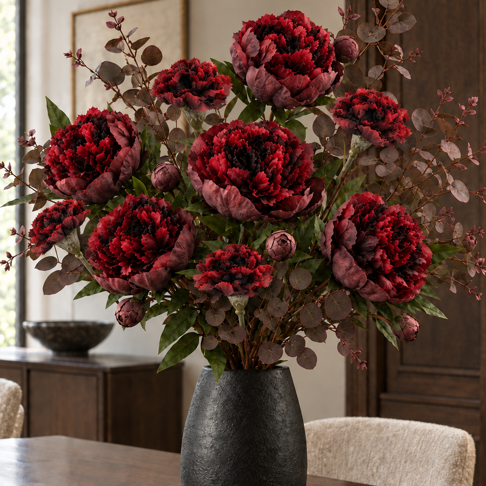 Close detail of layered burgundy peonies, closed buds, carnations and rounded eucalyptus leaves in the Nocturne Burgundy Bouquet