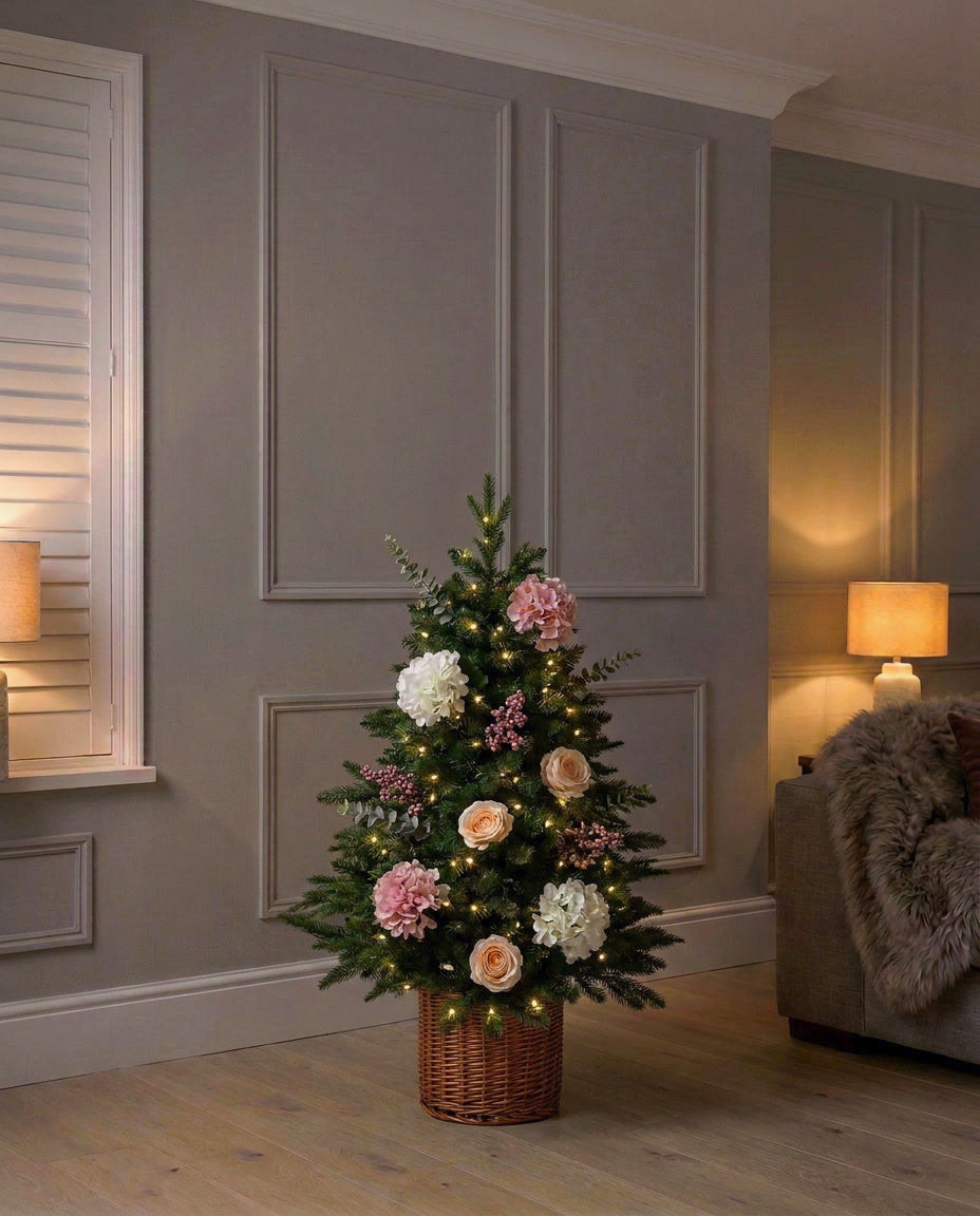 The artificial Winter Bloom Flower Christmas Tree, 90cm in its rattan pot, lit in a panelled living room in the evening