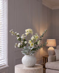 The Remembrance Posy: an artificial white wild meadow rose, cream crown hydrangea, white hellebore, gypsophila, eucalyptus and lamb's ear in the white ribbed Numa Squat Vase