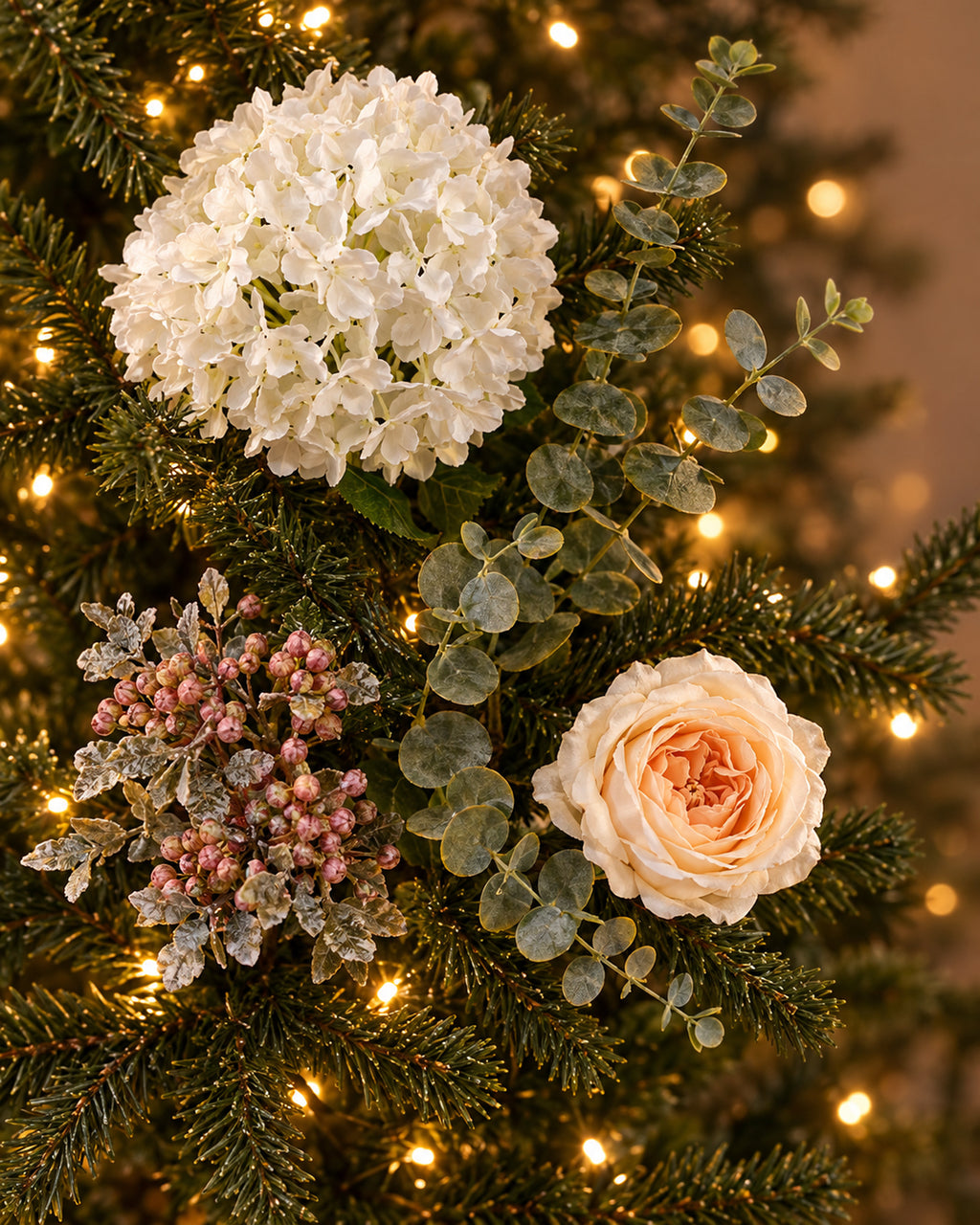 Artificial Winter Bloom flowers tucked into a lit tree as a styling guide; tree not included